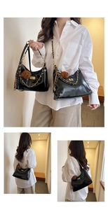 Details einer glänzenden schwarzen Schultertasche mit Goldkette und Bär-Anhänger