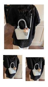 Detail of light blue bucket bag showing smooth leather texture and plush bear pendant