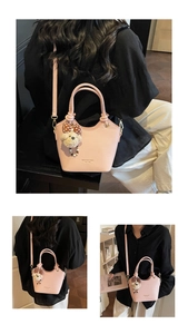 Detail of pink bucket bag with lychee grain leather, bear charm and golden branding