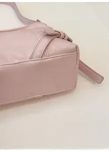 Close-up of the reinforced bottom base on a light pink textured leather tote bag