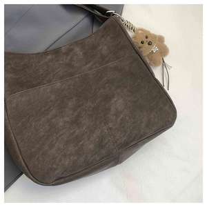 Close-up of retro brown leather tote with wrinkled texture and plush bear pendant