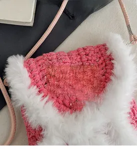 Close-up of pink woven crossbody phone bag with white plush trim and leather logo tag