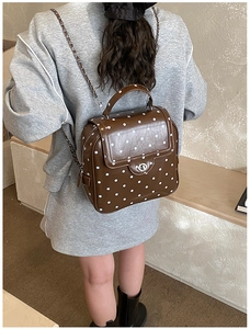 Detailed view of brown polka dot PU leather backpack with silver chain and metal turn lock