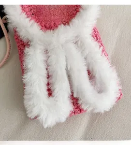Detail of pink hand-knitted bag featuring white faux fur trim and Hand Made leather label