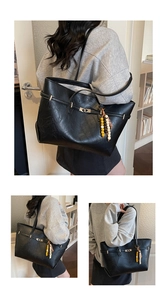 Detail of black large capacity tote bag with silver buckle and colorful beaded pendant