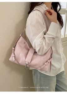 Detail of pink hobo bag with silver buckle and leather strap on model outfit