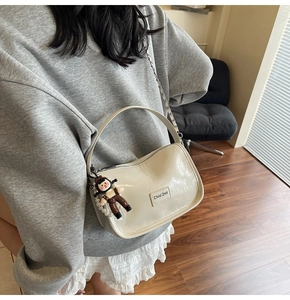 Détail du sac polochon en cuir verni plissé blanc cassé avec chaîne et perles