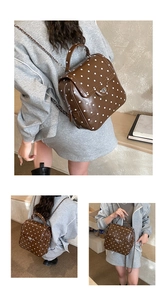 Detail of coffee polka dot backpack featuring metal twist lock and chain strap elements