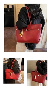Detail of red leather tote bag with metallic twist lock and ethnic beaded charm