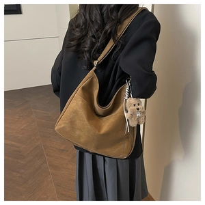 Brown faux suede tote bag with plush puppy charm shown on a stylish model outfit