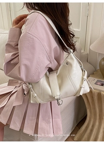 Detail of a minimalist hobo bag in cream leather featuring an adjustable shoulder strap