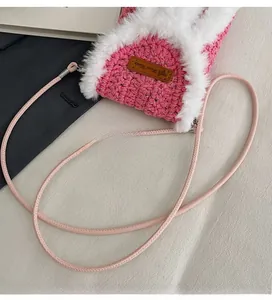 Detailed macro view of pink knit crossbody bag featuring white faux fur trim and leather tag