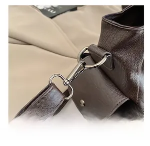 Detailed close-up of dark brown leather tote bag with metallic strap hook and texture