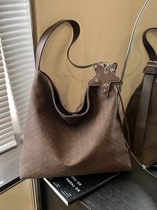 Deep brown woven leather tote bag with star charm and wide shoulder strap in studio light