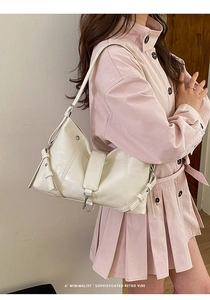 Detailed shot of a minimalist cream leather tote bag with retro metal buckle on a model