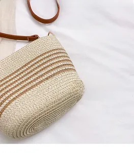 Detailed close-up of straw bucket bag with brown stripes and leather shoulder strap