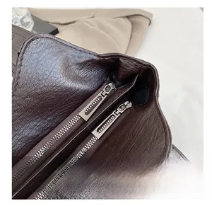 Macro detail of smooth dual metal zippers on brown lychee texture leather tote bag