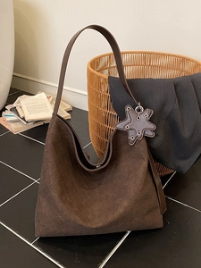 Large dark brown woven hobo bag with star charm detail on black tile flooring