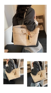 Close-up of beige tote bag with litchi texture, metal buckle and ethnic beaded tassel