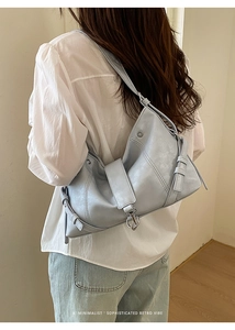 Detail of light blue vintage shoulder bag showing silver buckle and strap texture on model