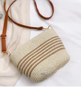 Detail of hand-woven straw bucket bag featuring brown stripes and leather strap
