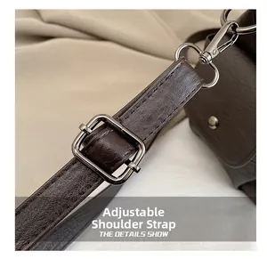 Close-up of adjustable brown leather shoulder strap with durable metal buckle and spring hook