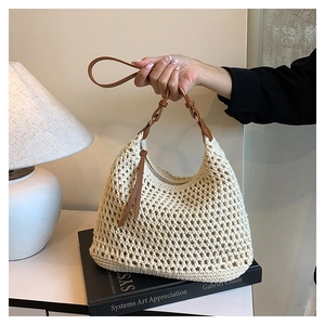 Detail of crochet hollow weave handbag with leather strap and tassel in soft warm light