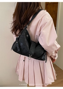 Detail showing the minimalist black leather shoulder bag with wide strap and silver ring buckle