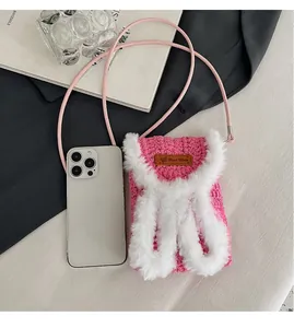 Close-up of pink hand-knitted mini phone bag with white faux fur trim and leather label