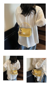 Détails d'un sac à main jaune verni avec bandoulière chaîne dorée et poignée anneau