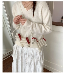 Detail of handmade horse-shaped crossbody bag with cream pearls and red accents