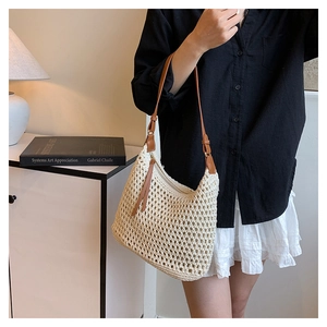 Detail of crochet hollow texture on beige beach bag with brown leather shoulder strap