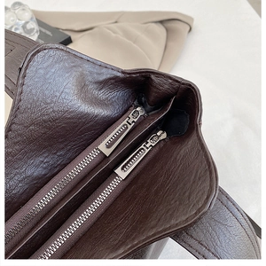 Macro view of dark brown pebbled leather texture and silver dual metal zippers