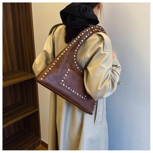 Detail of dark brown leather hobo bag featuring vintage rivets and silver metal hardware