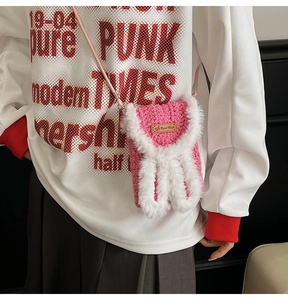 Detailed macro view of handmade pink knit crossbody bag with plush rabbit ears and label