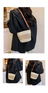 Detail shot of woven straw bucket bag with brown stripes and leather shoulder strap