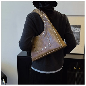 Detail of vintage brown leather shoulder bag with silver rivets and buckle texture
