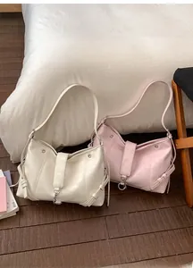 Detail view of cream and pale pink leather tote bags with metal ring and strap accents