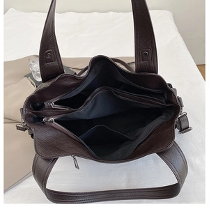Interior view of large leather tote bag showing multi-layer compartments and deep brown texture
