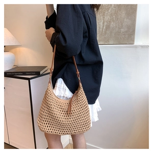 Detail of hand-woven hollow straw shoulder bag with elegant brown leather strap