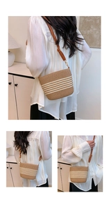 Close-up of woven straw bucket bag with white stripes and brown leather strap detail
