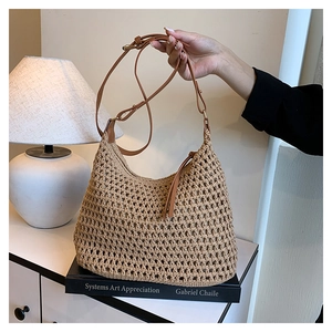 Detail of beige crochet hollow tote bag with adjustable brown leather shoulder strap
