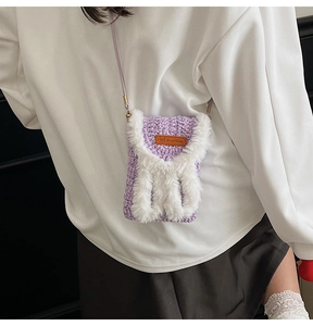 Detail of handmade purple knit crossbody bag with plush trim and Hand Made leather tag