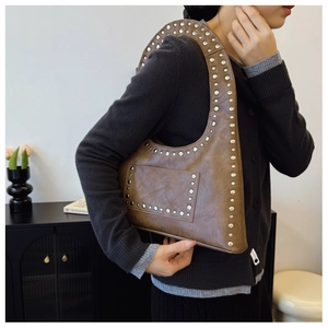 Detail of vintage brown shoulder bag with silver rivets and textured oil wax finish