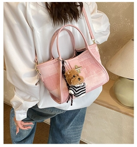 Detail of pink textured woven bucket bag with golden twist lock and teddy bear charm