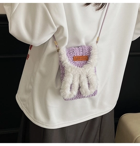 Detail view of purple crochet crossbody bag with plush rabbit ears and handmade leather tag