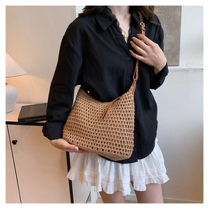Detail of hand-woven straw crossbody bag with brown leather strap and mesh texture