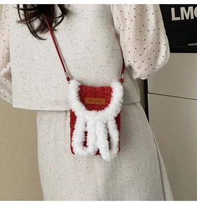 Detail of red knitted crossbody bag with white faux fur trim and Hand Made leather label