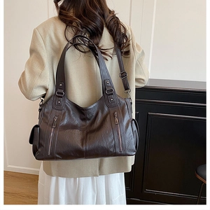 Detail view of large dark brown tote bag with glossy leather texture and zipper accents