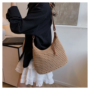 Close-up of a hollow-out woven tote bag with brown leather strap in a home setting